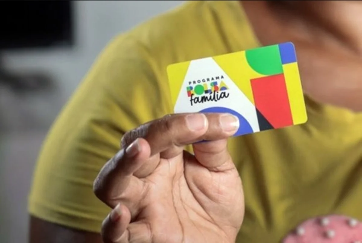 Mão segurando um cartão do Bolsa Família - Metrópoles