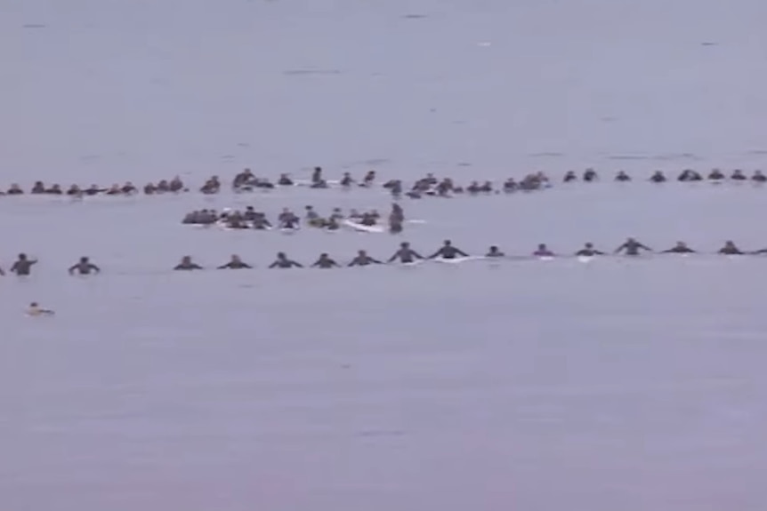 An archival image of surfers making a circle in the water to commemorate those who died at Gracetown
