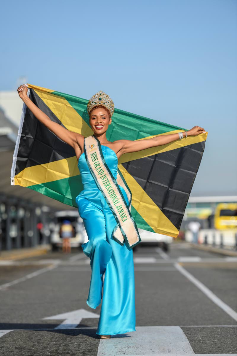 Simone Gardner proudly displays the Jamaican flag as she poses for the camera ahead of her departure from Norman Manley International Airport for the Miss Grand International competition in Thailand.