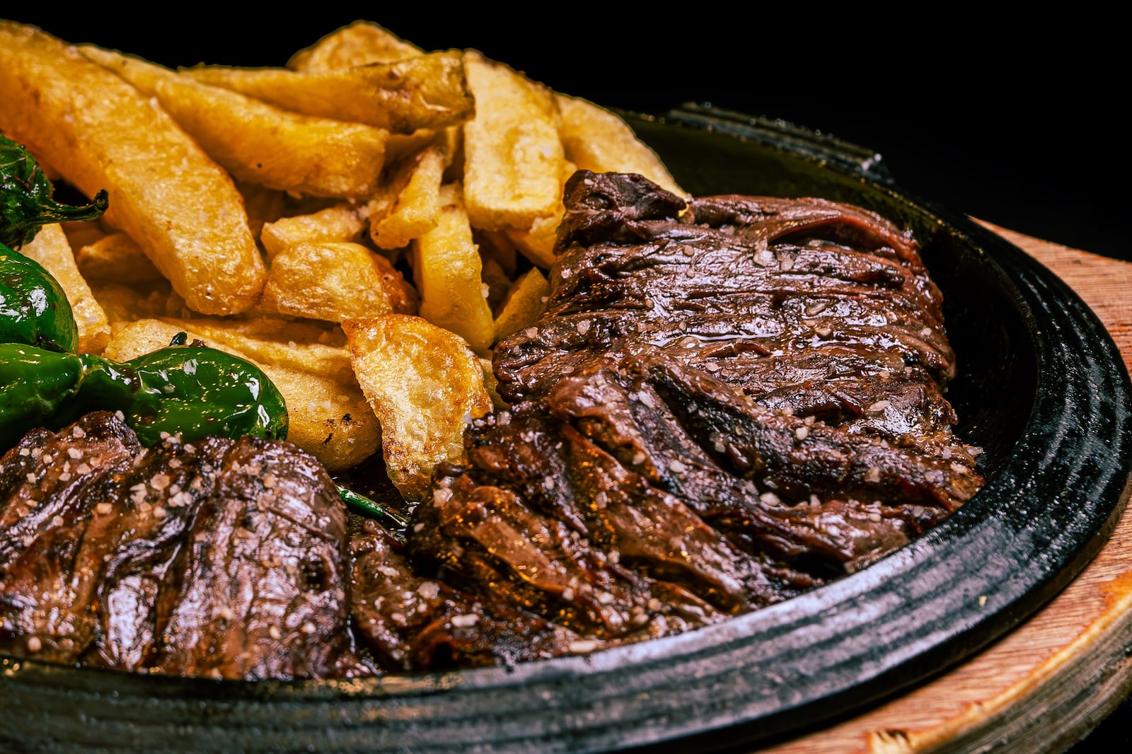 Bife grelhado suculento acompanhado de batatas fritas crocantes e pimentões verdes em um prato rústico Nano Erdozain