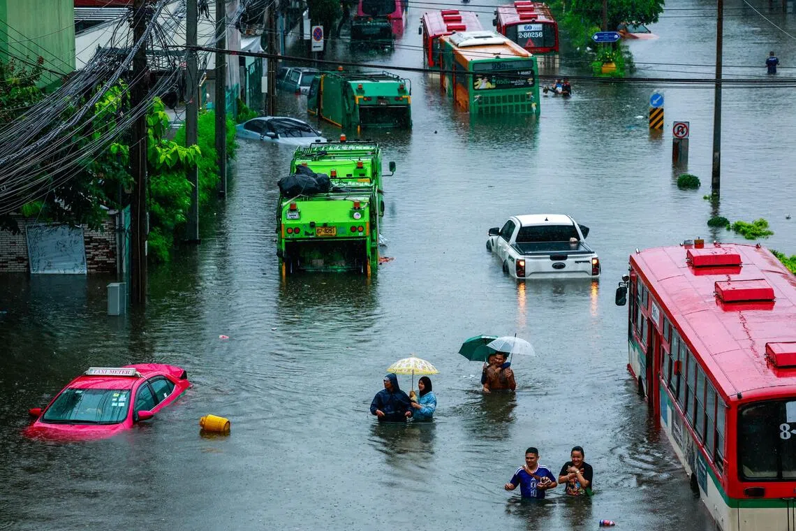 People wade through a flooded street during heavy rain in Bangkok, on Sept 26.
