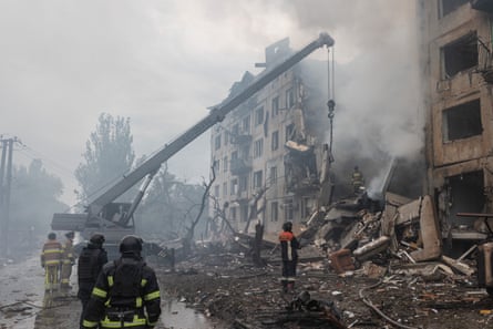 Ukrainian firefighters searching the rubble for civilians as smoke rises