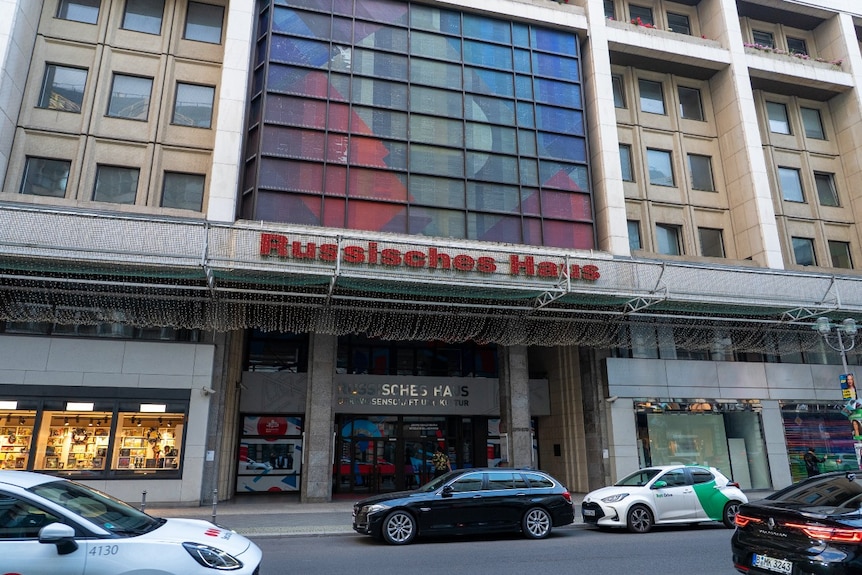 The exterior of a large building. The words Russisches Haus are visible above its entrance.