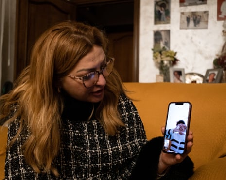 A young woman makes a heart gesture with her hands on a phone's screen during a video call with an older woman
