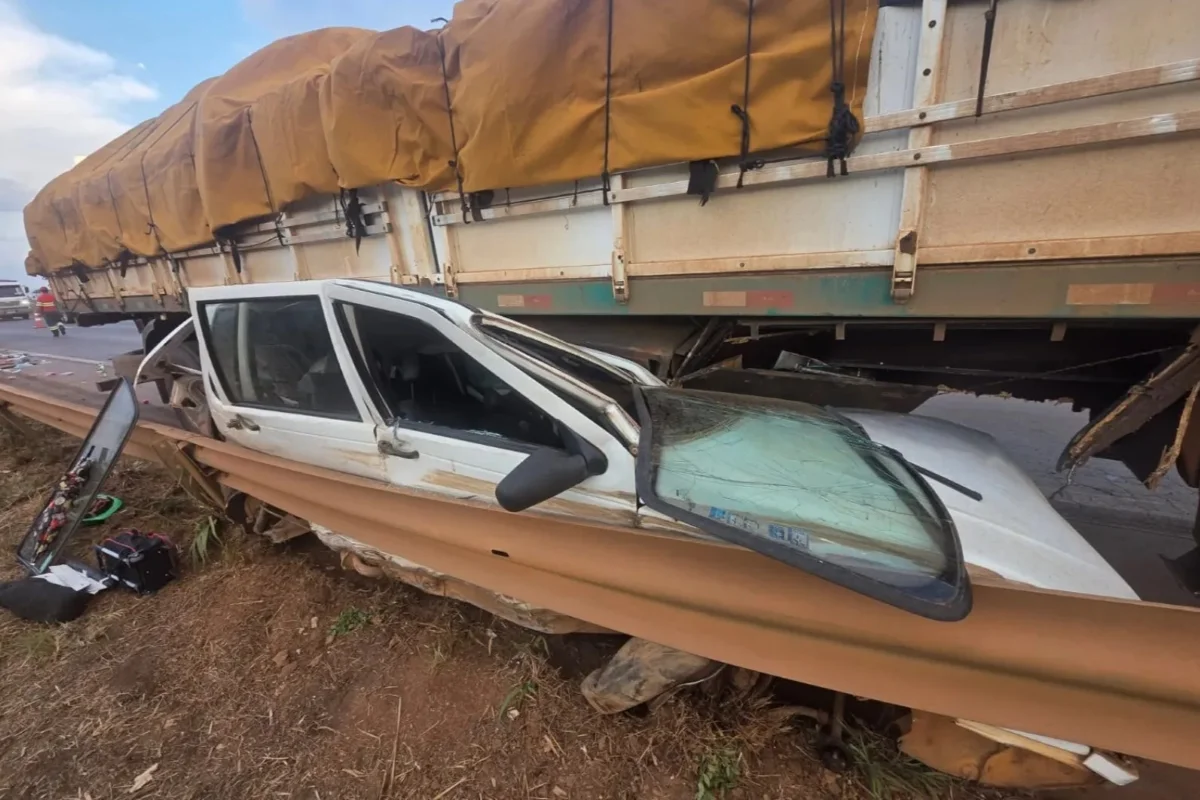 Imagem colorida mostra Fiat Uno prensado por caminhão - Metrópoles