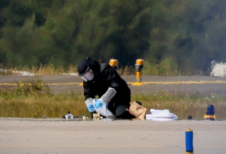 A police officer in protective clothing works examining an object on the tarmac at Leipzig/Halle airport