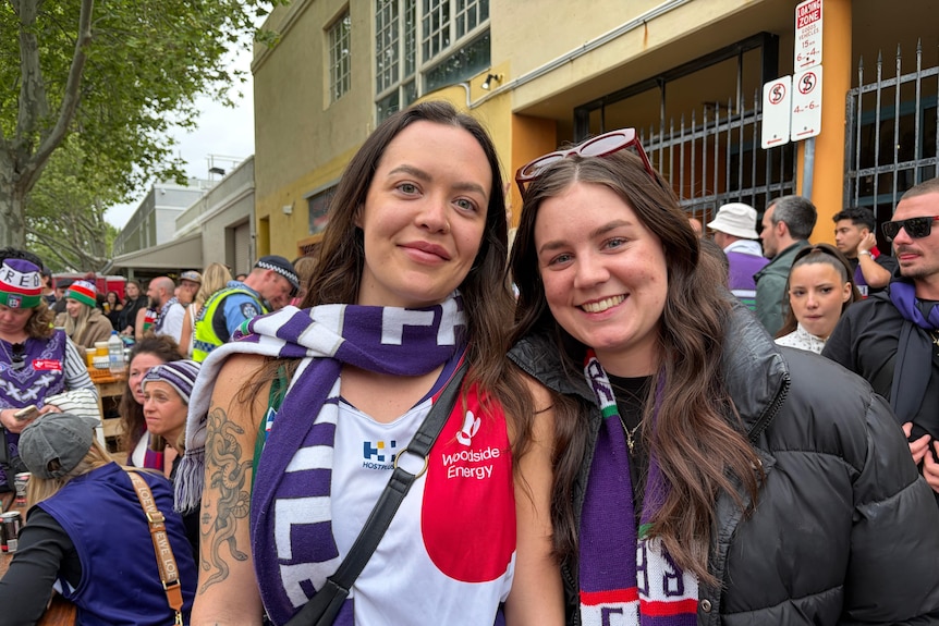 Two woman have a purple scarf on in crowds.