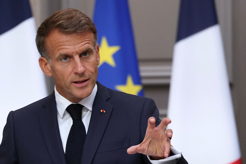 Emmanuel Macron speaking with a hand reached out.