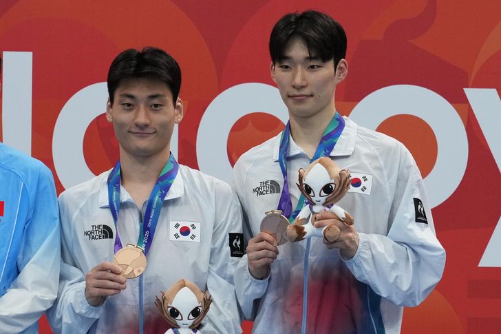 Shin Jung-whi, right, and Kim Yeong-taek of South Korea pose with their medals after winning bronze in men's synchronized 10m springboard final at the Asian Games in Tokyo, Japan, Sunday. AP-Yonhap