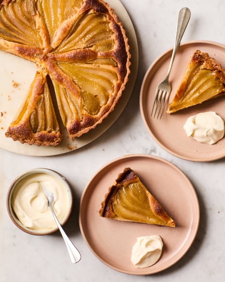 Overhead view of a poached pear and almond tart, with plated slices topped with cream