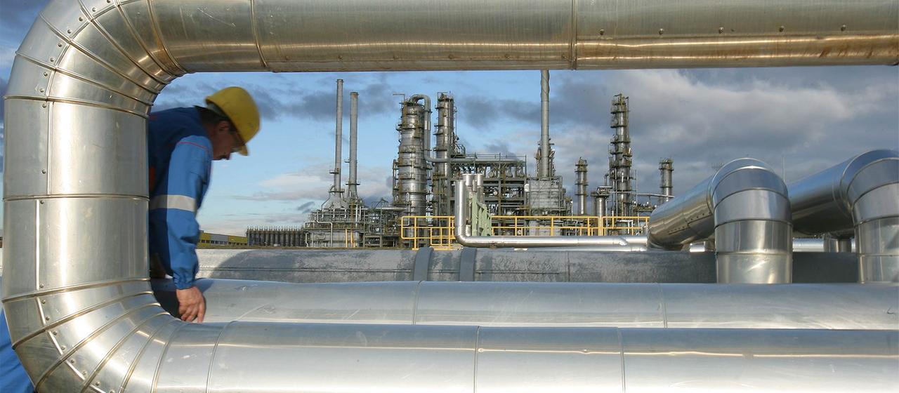 In der Raffinerie in Leuna geht ein Mitarbeiter an den Rohren einer Pumpstation entlang.